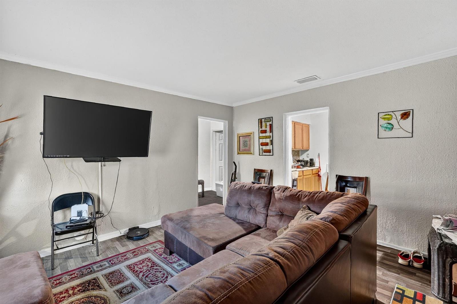 A living room features a brown sectional sofa, a wall-mounted television, and a patterned rug — 1030 NW 13 Avenue, FL 34475, FL