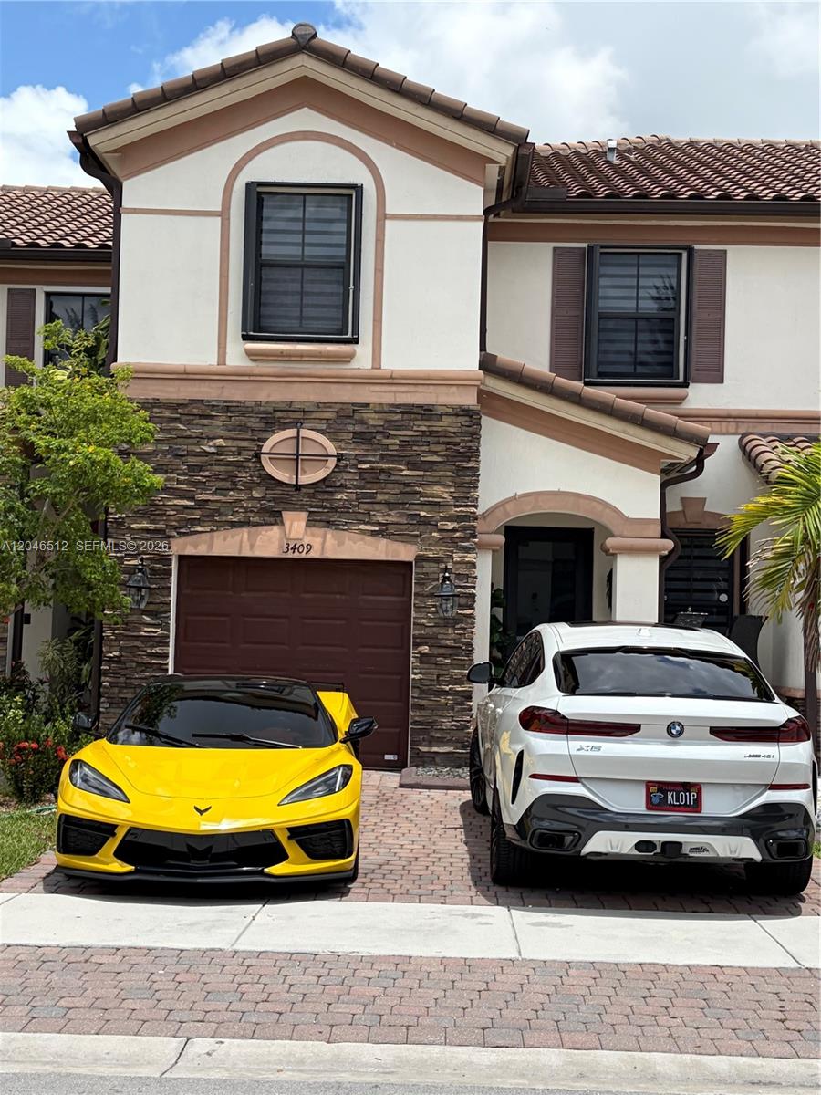 A two-story house with a stone facade, a garage, and two cars parked in the driveway — 3409 W 92nd Pl # 3409, Hialeah FL 33018, HIALEAH, FL