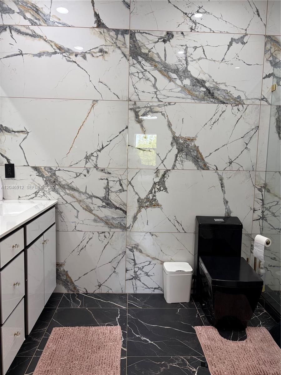 A bathroom features white marble-patterned wall tiles, black floor tiles, and a black toilet — 3409 W 92nd Pl # 3409, Hialeah FL 33018, HIALEAH, FL