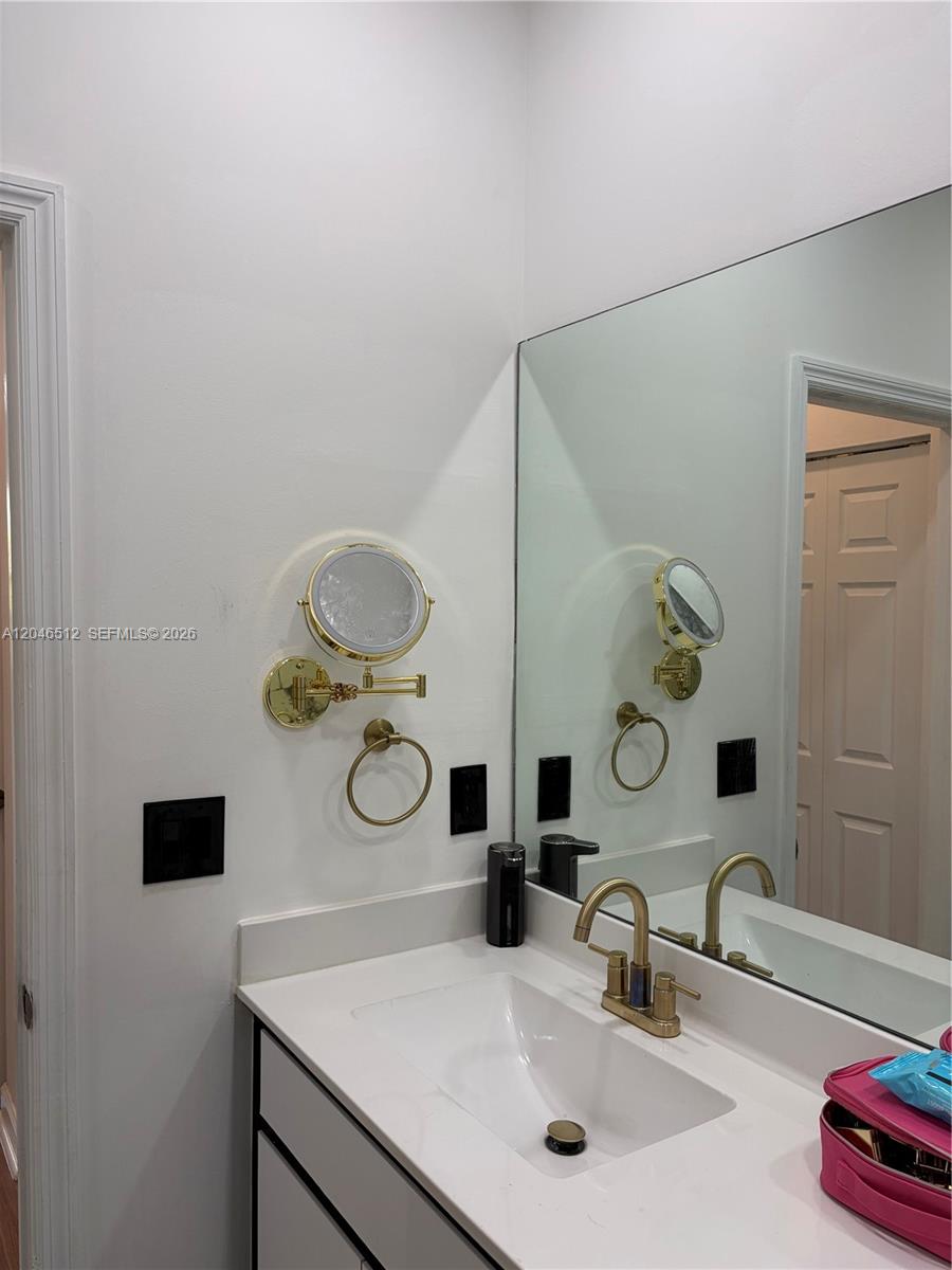 A bathroom vanity features a white countertop, gold faucet, and a wall-mounted magnifying mirror — 3409 W 92nd Pl # 3409, Hialeah FL 33018, HIALEAH, FL