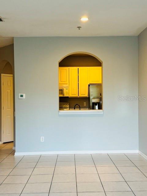 A light blue wall features an arched pass-through window looking into a kitchen with yellow cabinets — 7135 YACHT BASIN AVENUE UNIT 239, ORLANDO, FL