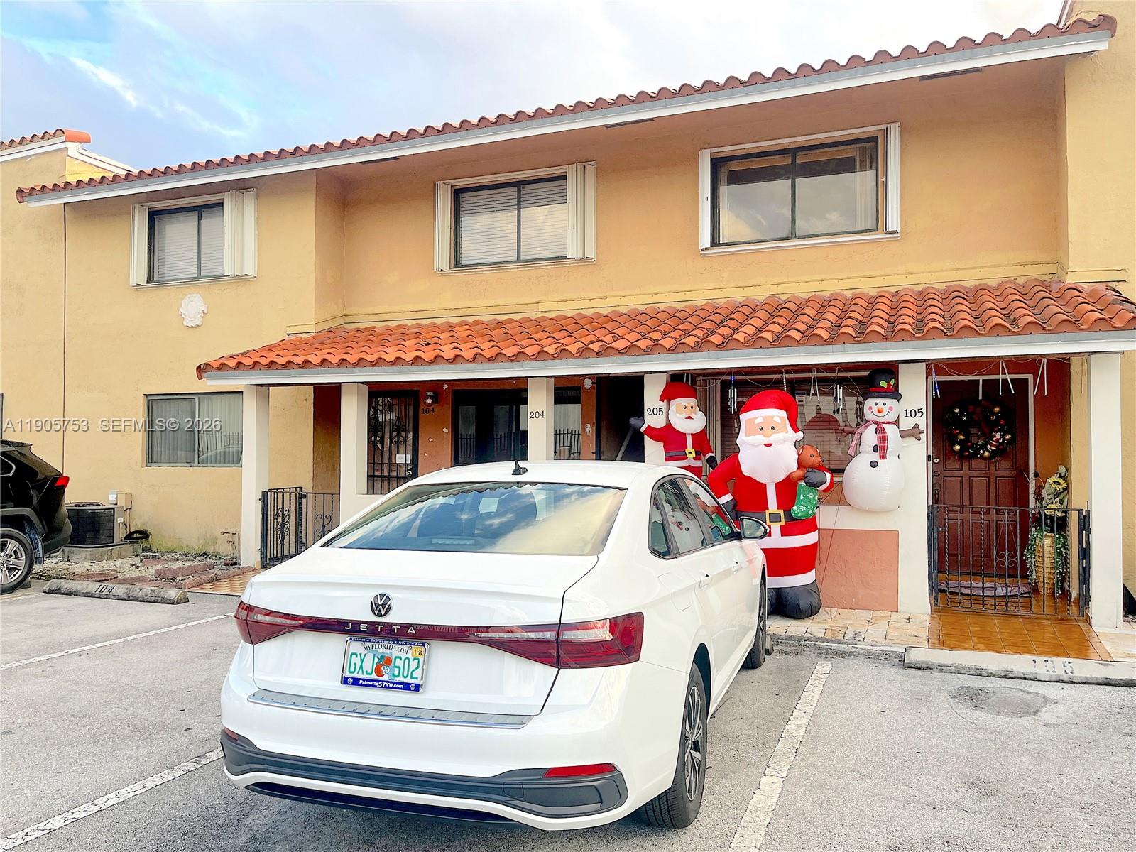 A white sedan is parked in front of a two-story building with holiday inflatables — 2740 W 63rd St # 104, Hialeah FL 33016, HIALEAH, FL