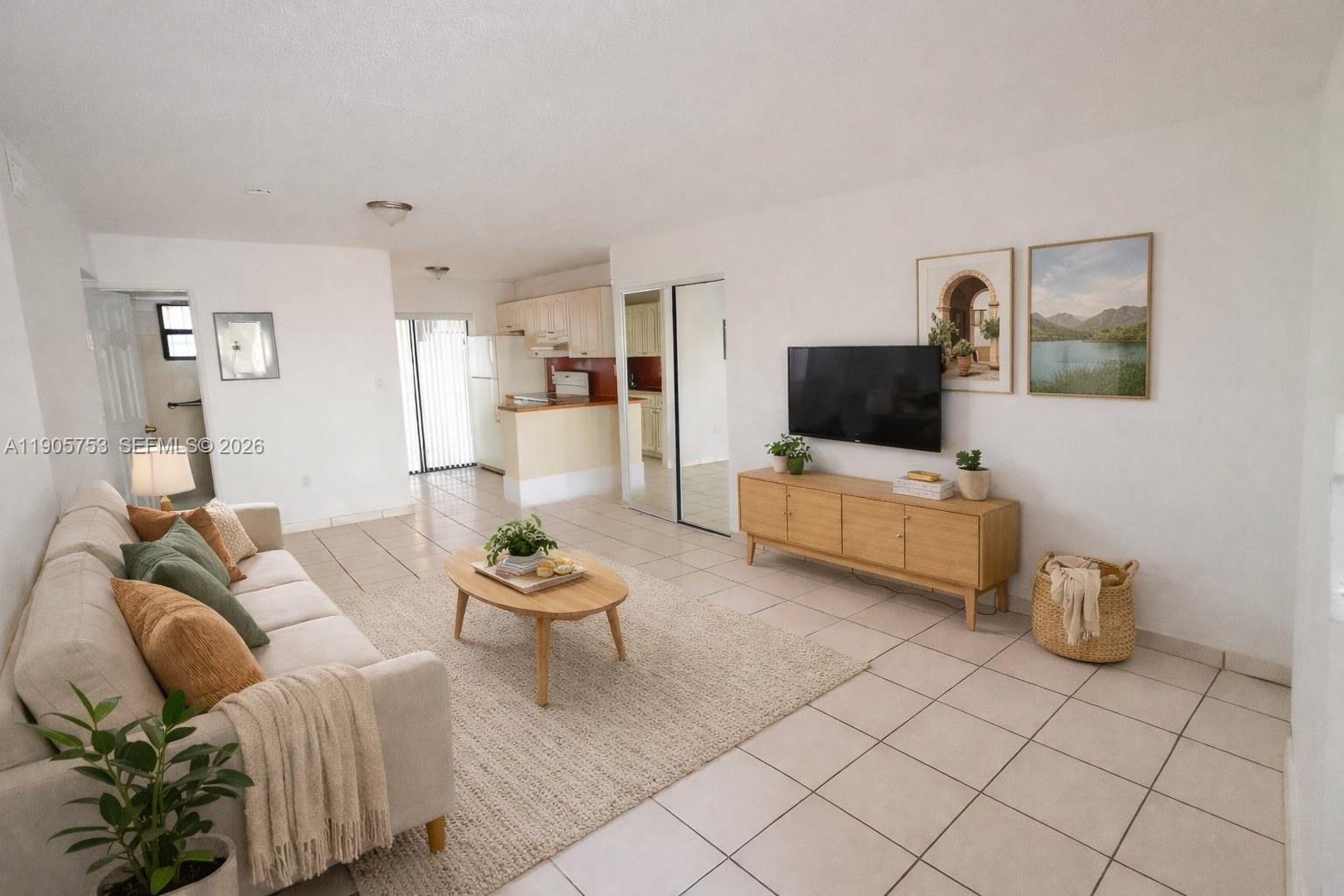 A living room features a beige sofa, a wooden coffee table, and a wall-mounted television — 2740 W 63rd St # 104, Hialeah FL 33016, HIALEAH, FL