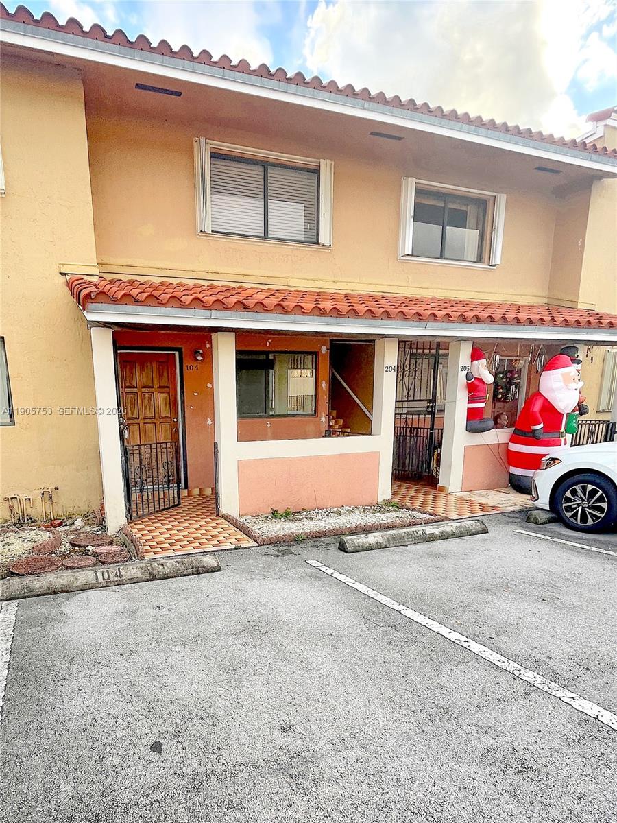 An exterior view of a two-story apartment building with a tiled roof and parking spaces — 2740 W 63rd St # 104, Hialeah FL 33016, HIALEAH, FL