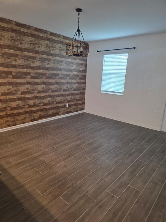 A dining room features wood-look tile flooring, a rustic accent wall, and a hanging light fixture — 13882 TITLE WAY, WINTER GARDEN, FL