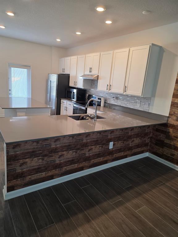 A kitchen features white cabinets, gray countertops, and a wood-paneled island base — 13882 TITLE WAY, WINTER GARDEN, FL