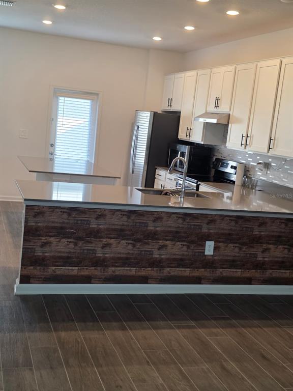 A kitchen features white cabinets, stainless steel appliances, and a wood-patterned island base — 13882 TITLE WAY, WINTER GARDEN, FL