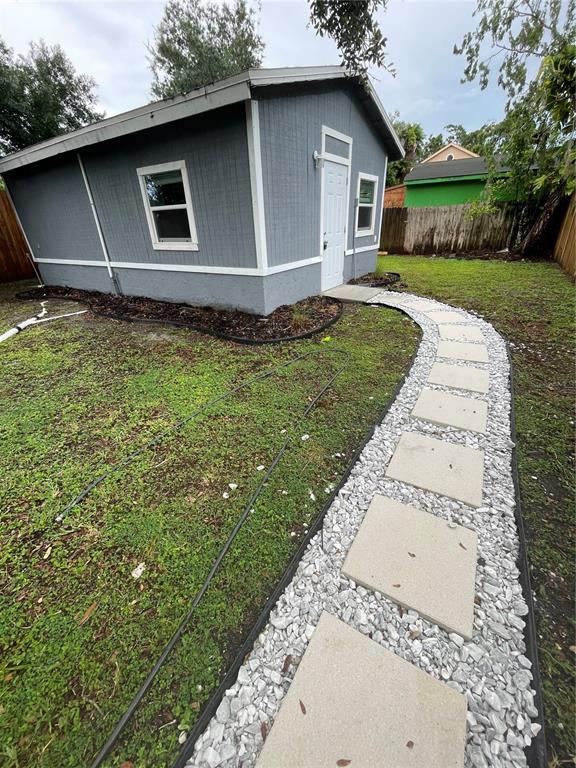 A gray shed with a white door and a stone paver walkway in a yard — 3419 19TH STREET E UNIT Back ADU, BRADENTON, FL