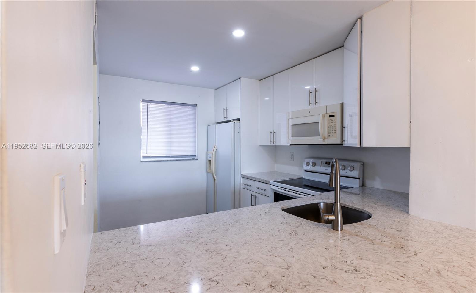 A kitchen features white cabinets, stone countertops, stainless steel appliances, and a sink — 19701 SW 114th Ave # 364, Miami FL 33157, MIAMI, FL