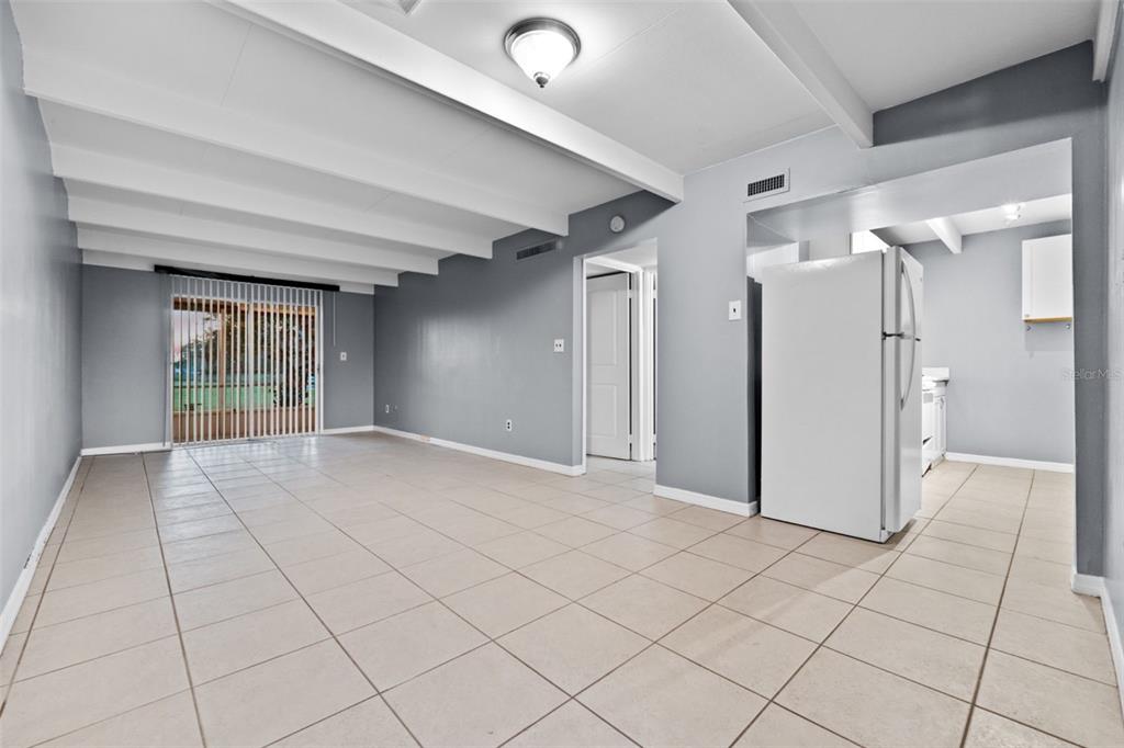 An open-concept living area features gray walls, white exposed ceiling beams, and light-colored tile flooring — 3515 CLUB CIRCLE, LAKESHORE, FL
