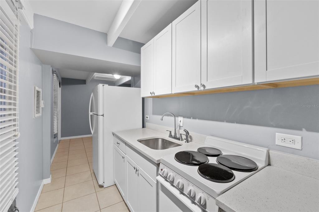 A kitchen features white cabinets, a stainless steel sink, and a white electric stove — 3515 CLUB CIRCLE, LAKESHORE, FL