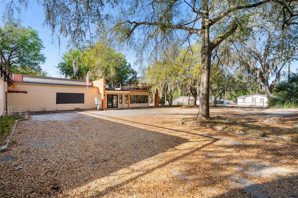 An exterior view of a single-story commercial building with a large, leaf-covered parking lot — 519 NW 10TH AVENUE, GAINESVILLE, FL