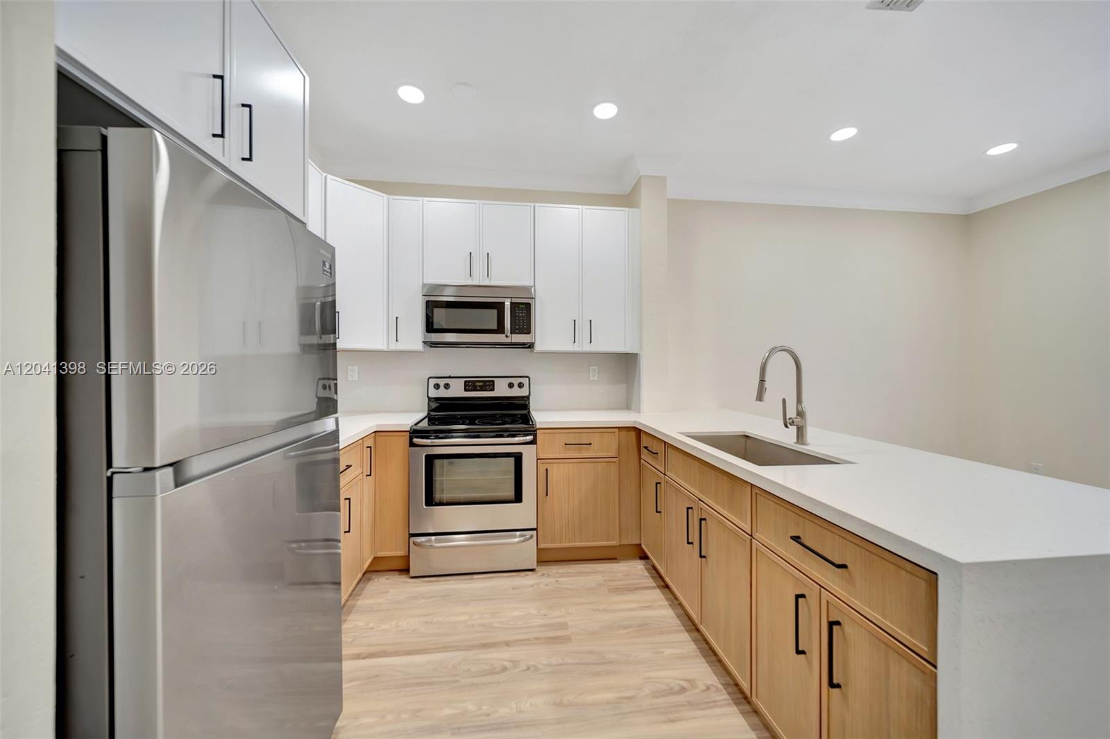 A kitchen features white upper cabinets, light wood lower cabinets, stainless steel appliances, and countertops — 17620 NW 73rd Ave # 17, Hialeah FL 33015, HIALEAH, FL