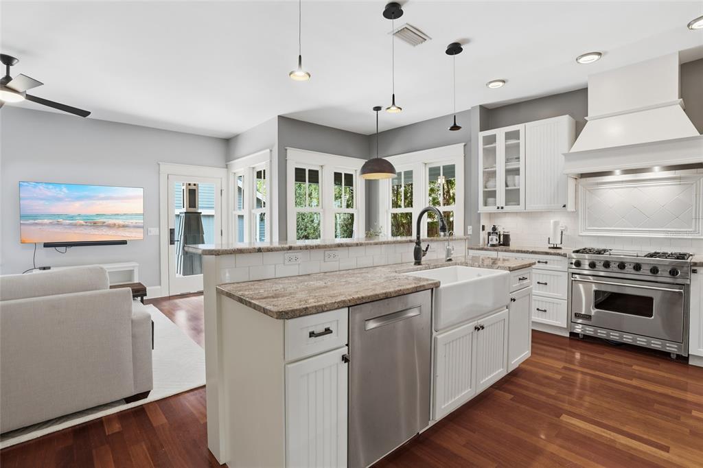 A kitchen features white cabinetry, a farmhouse sink, stainless steel appliances, and hardwood floors — 2116 W WATROUS AVENUE, TAMPA, FL