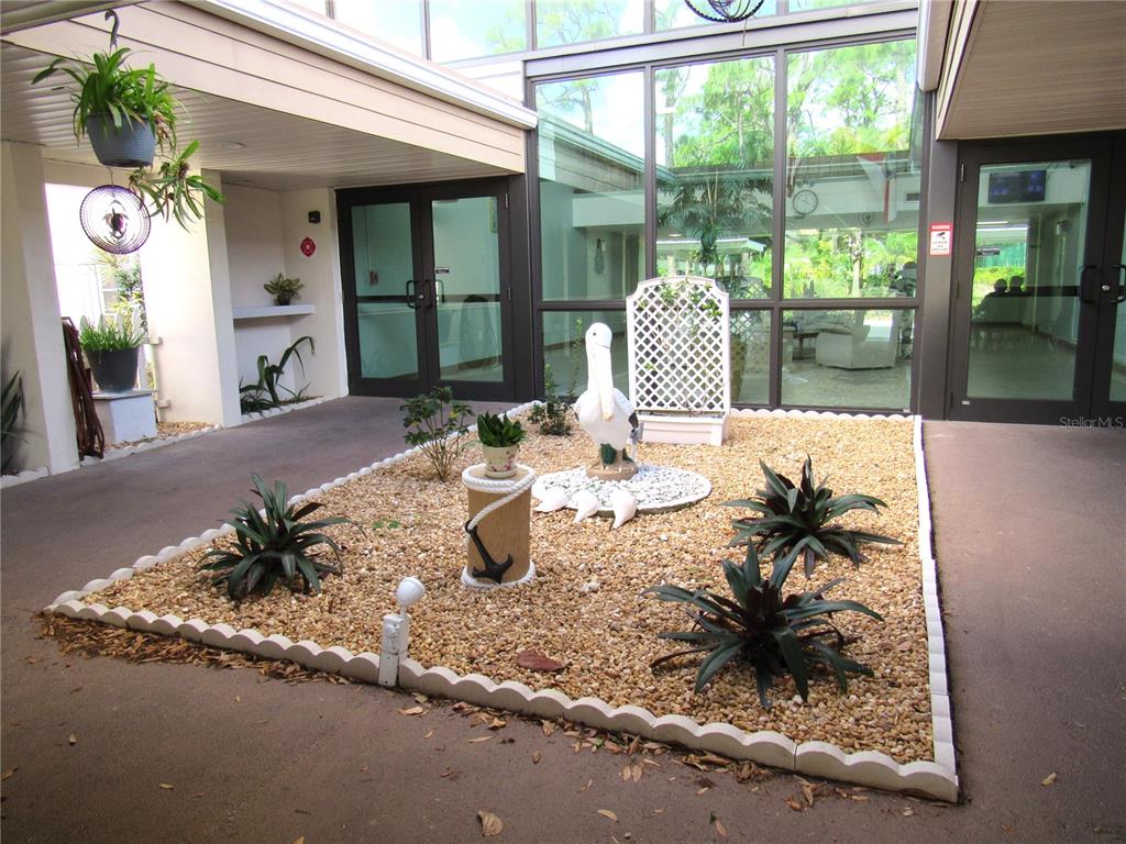 A courtyard features a gravel garden bed with a pelican statue and potted plants — 21260 BRINSON AVENUE UNIT 212, PORT CHARLOTTE, FL