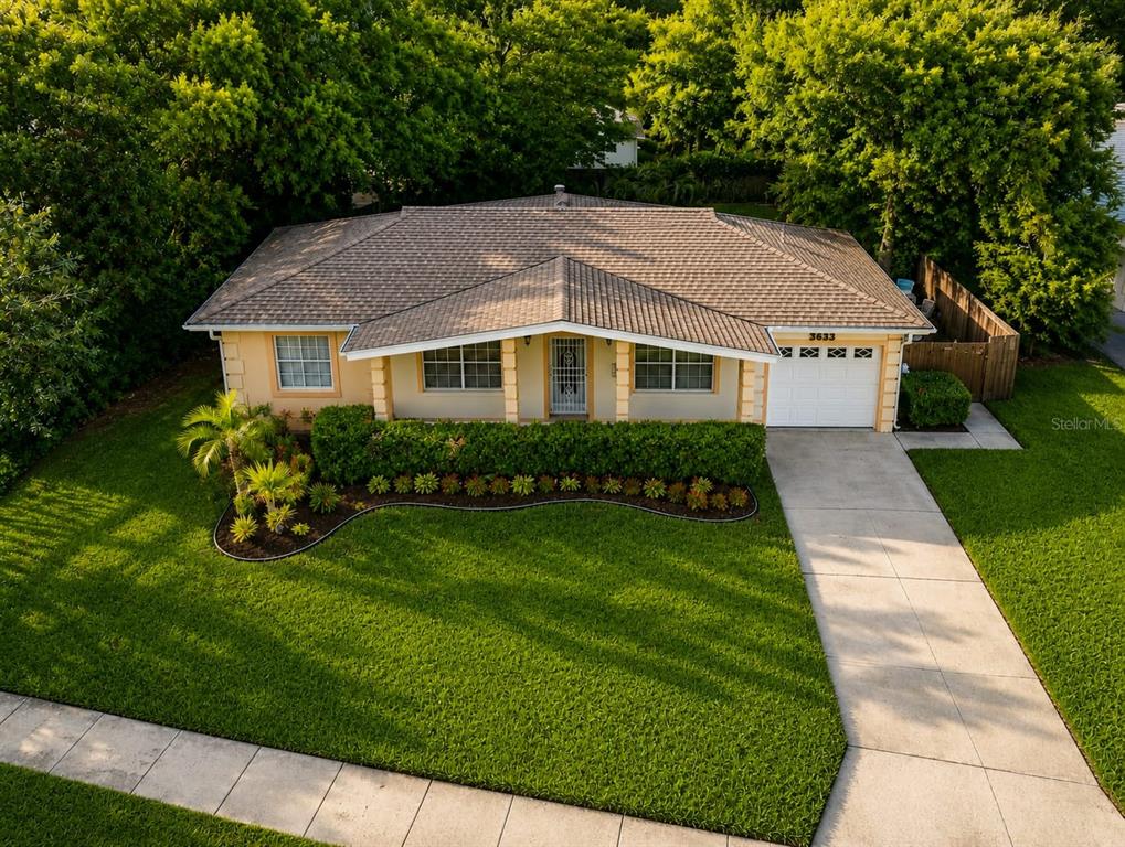 An aerial view shows a single-story house with a tan exterior, tiled roof, and driveway — 3633 RANCHWOOD ROAD, ORLANDO, FL