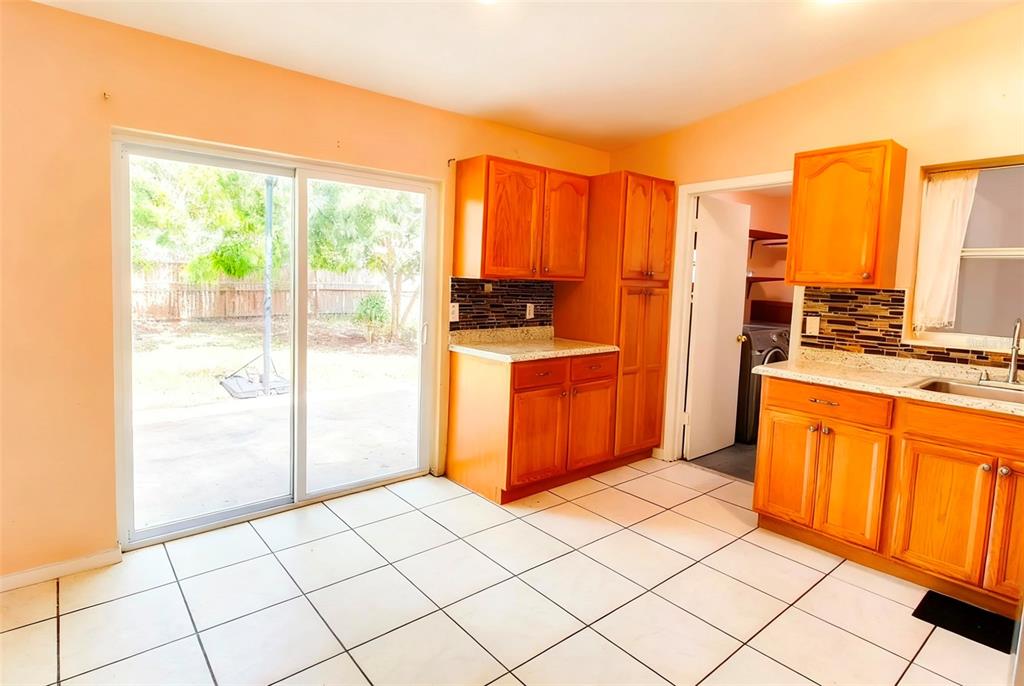 A kitchen with wood cabinets, tiled floors, and a sliding glass door to the yard — 3633 RANCHWOOD ROAD, ORLANDO, FL