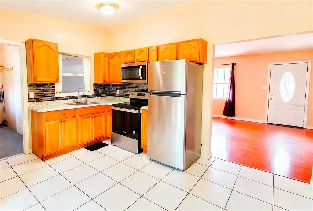 A kitchen with wood cabinets, stainless steel appliances, and white tile flooring — 3633 RANCHWOOD ROAD, ORLANDO, FL