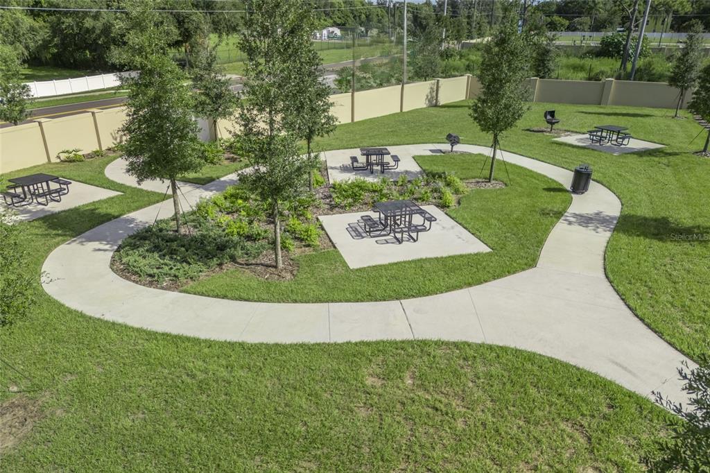 An outdoor park area features concrete walkways, picnic tables, and young trees on a lawn — 2692 CAVANAUGH DRIVE, ORLANDO, FL