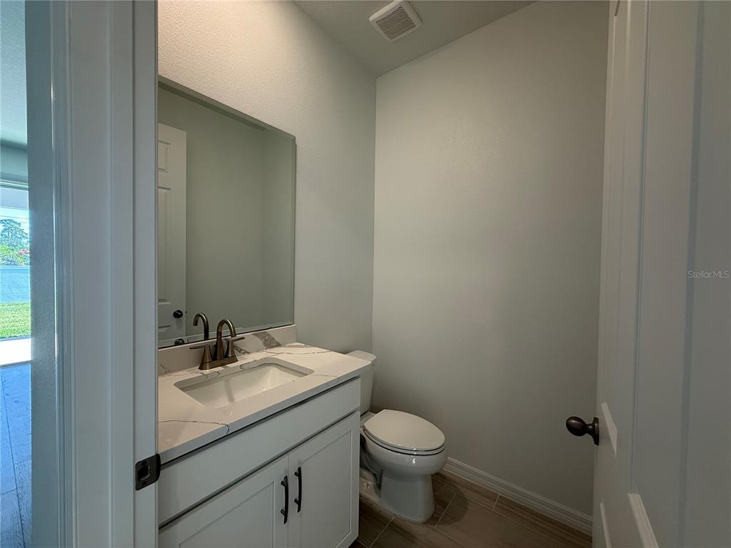 A small bathroom features a white vanity with a marble countertop and a toilet — 2692 CAVANAUGH DRIVE, ORLANDO, FL
