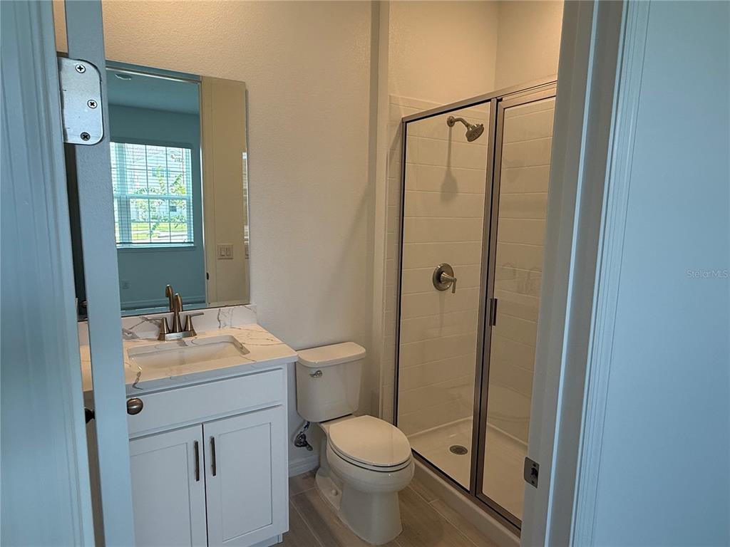 A bathroom features a white vanity with a marble countertop, a toilet, and a glass shower — 2692 CAVANAUGH DRIVE, ORLANDO, FL