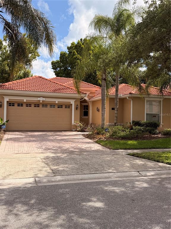 A single-story house with a tan exterior, red tile roof, and a two-car garage — 11316 RAPALLO LANE, WINDERMERE, FL