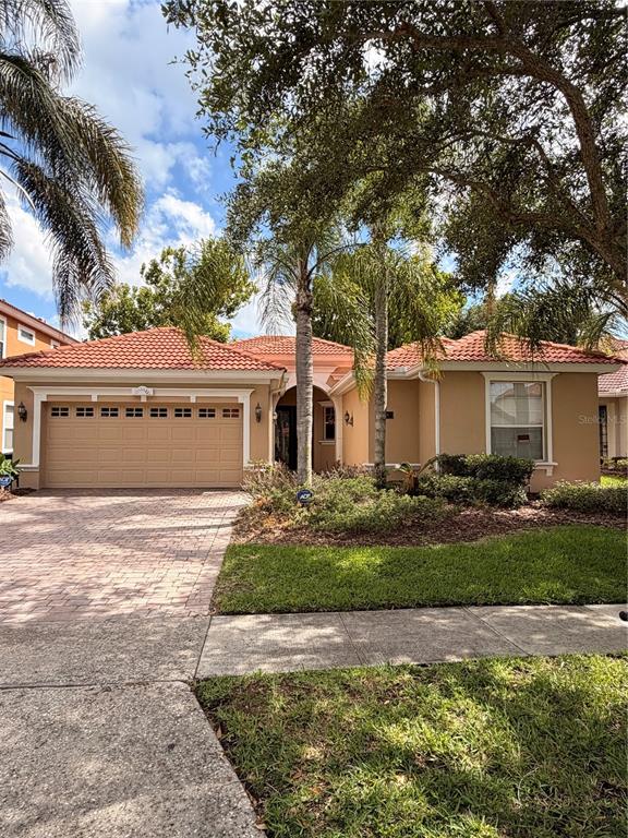 A single-story house with a tan exterior, a tiled roof, and a two-car garage — 11316 RAPALLO LANE, WINDERMERE, FL