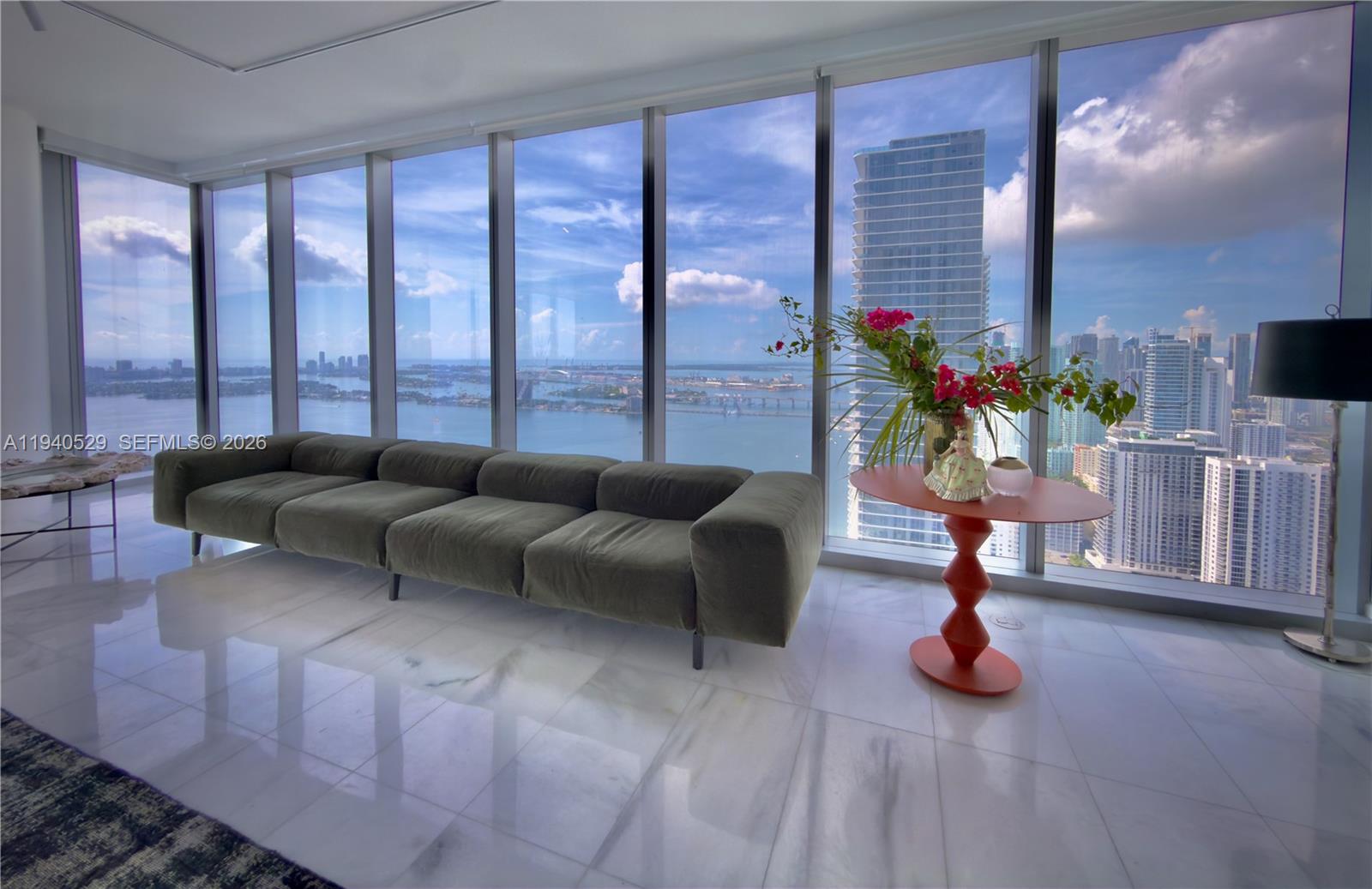 A modern living room features a green sofa, a sculptural table, and floor-to-ceiling windows — 700 NE 26th Terrace # 4403, Miami FL 33137, MIAMI, FL