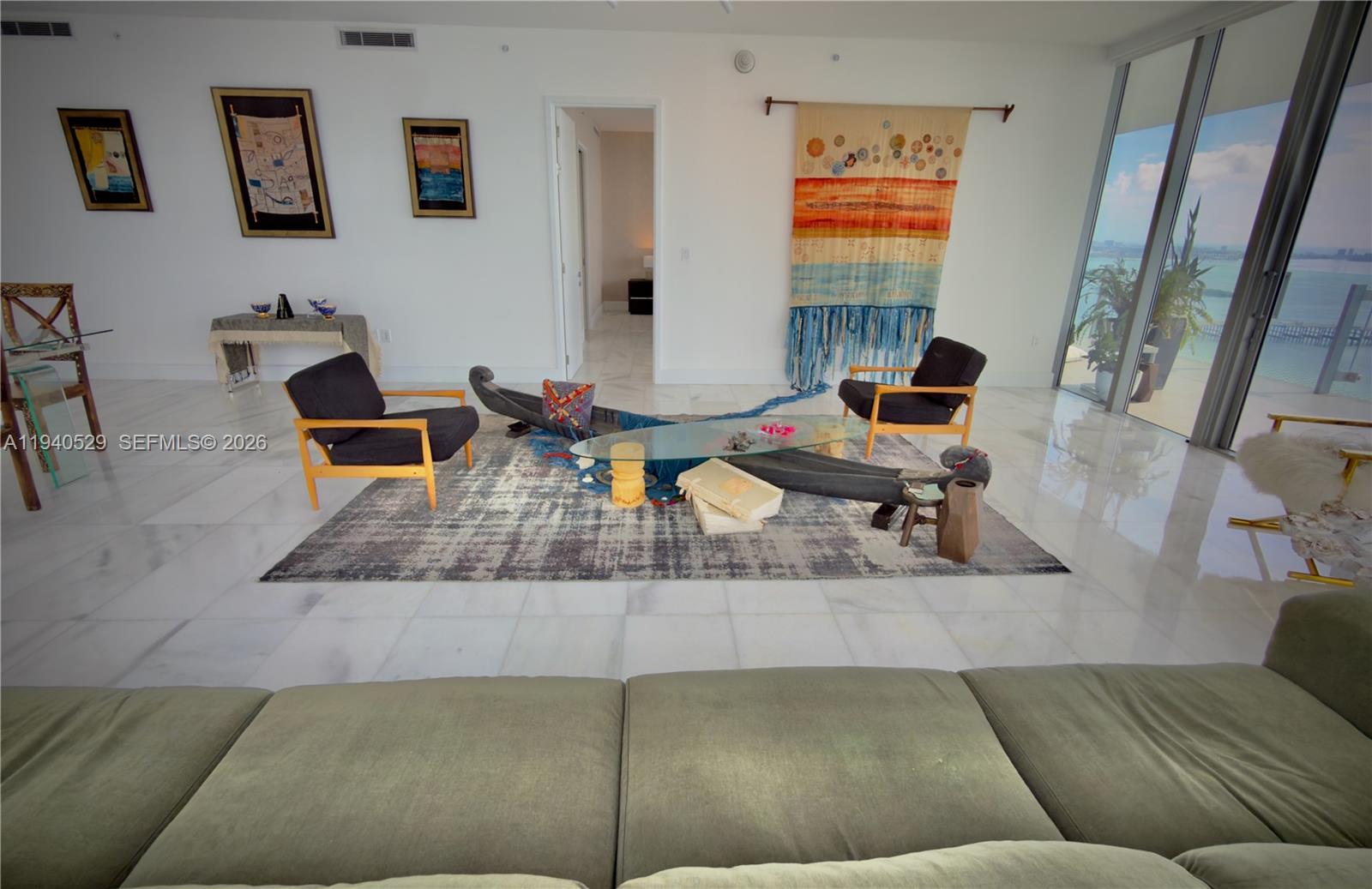 A living room features a glass coffee table, two black armchairs, and a large wall tapestry — 700 NE 26th Terrace # 4403, Miami FL 33137, MIAMI, FL