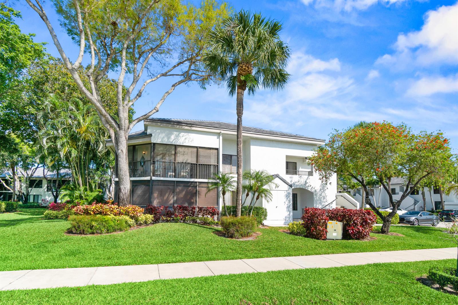 A two-story white residential building with a screened-in balcony stands on a grassy lawn — 7533 Glendevon Lane # 905, Delray Beach FL 33446, DELRAY BEACH, FL