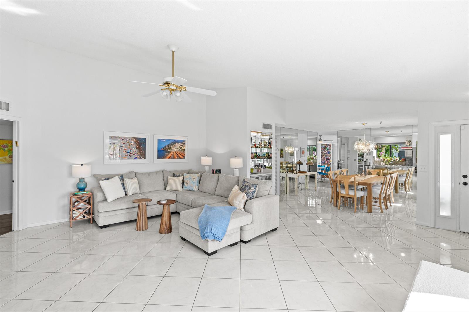 A bright living room features a large sectional sofa, tiled floors, and an adjacent dining area — 7533 Glendevon Lane # 905, Delray Beach FL 33446, DELRAY BEACH, FL