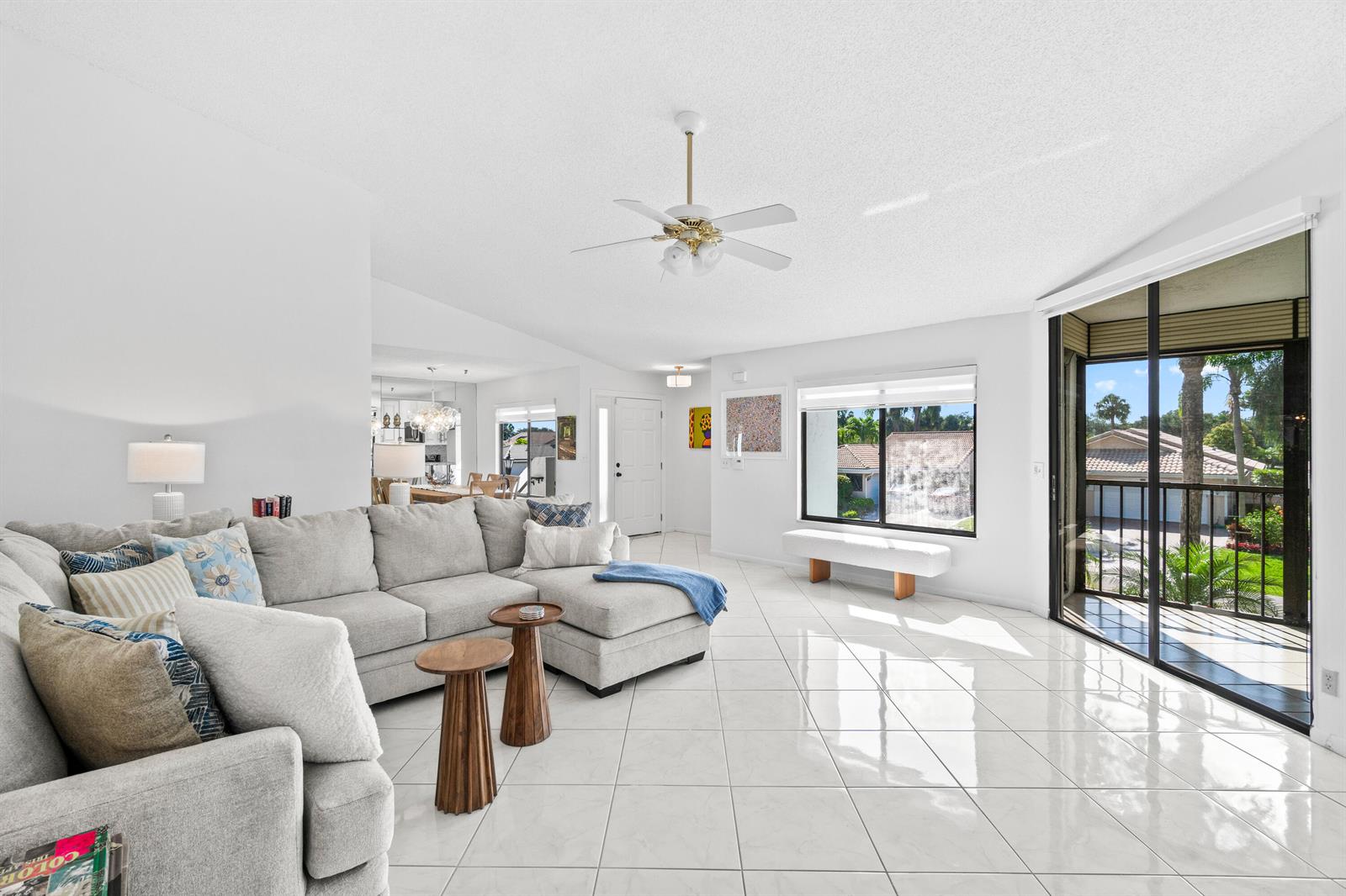 A bright living room features white tile floors, a gray sectional sofa, and a balcony — 7533 Glendevon Lane # 905, Delray Beach FL 33446, DELRAY BEACH, FL