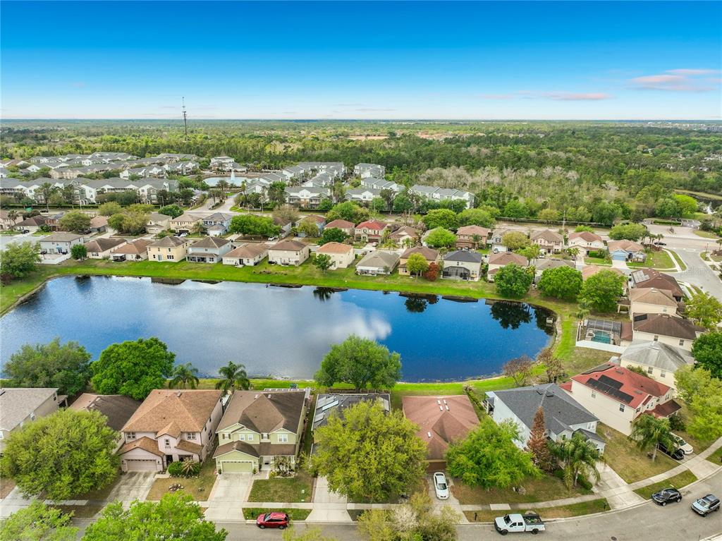 An aerial view shows a suburban neighborhood with houses surrounding a central retention pond — 14932 PERDIDO DRIVE, ORLANDO, FL