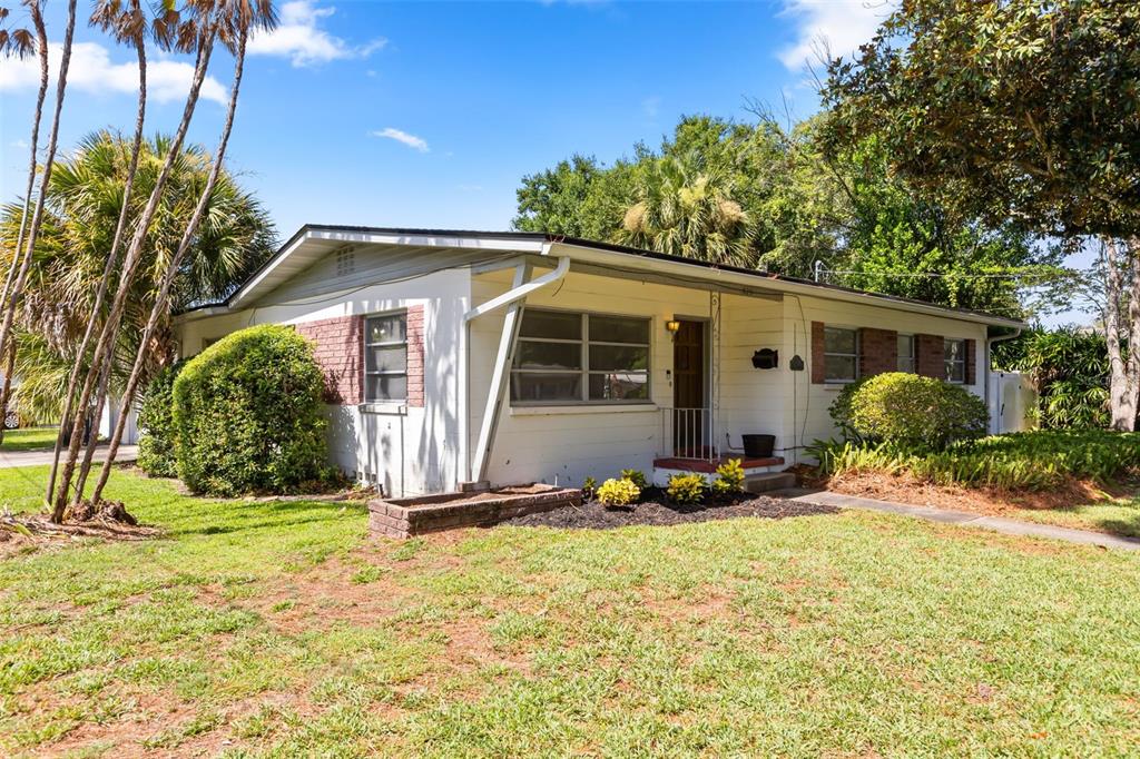 A single-story house with white siding, brick accents, and a front yard with palm trees — 820 RUGBY STREET, ORLANDO, FL