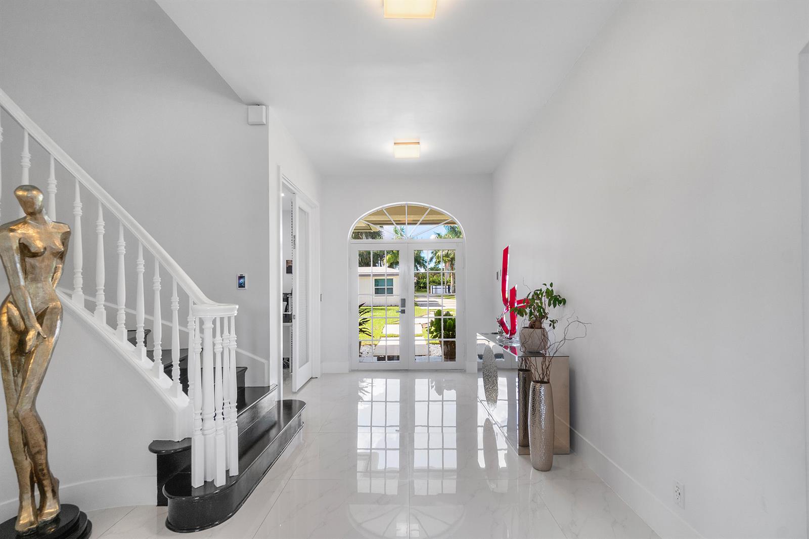 A white modern gate with black trim sits between two pillars surrounded by lush hedges — 5447 Center Street, Jupiter FL 33458, JUPITER, FL