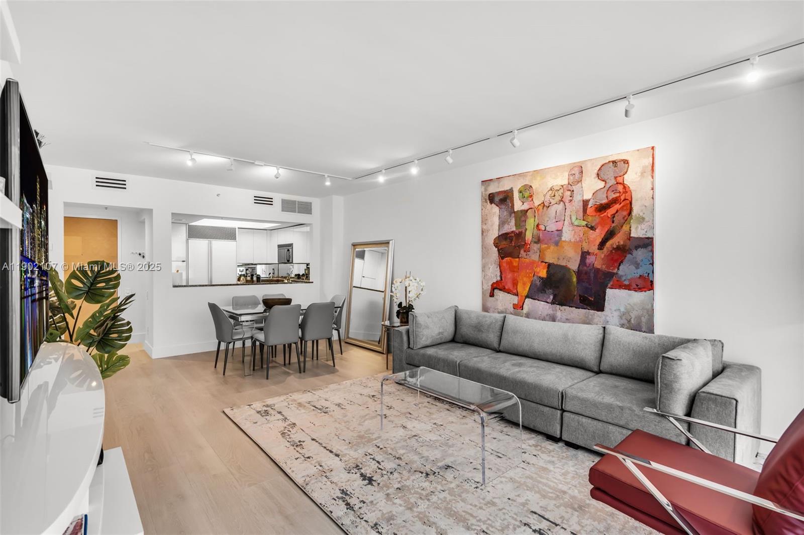 A living room features a grey sofa, a glass coffee table, and a large abstract painting — 1500 Ocean Dr # 1109, Miami Beach FL 33139, MIAMI BEACH, FL