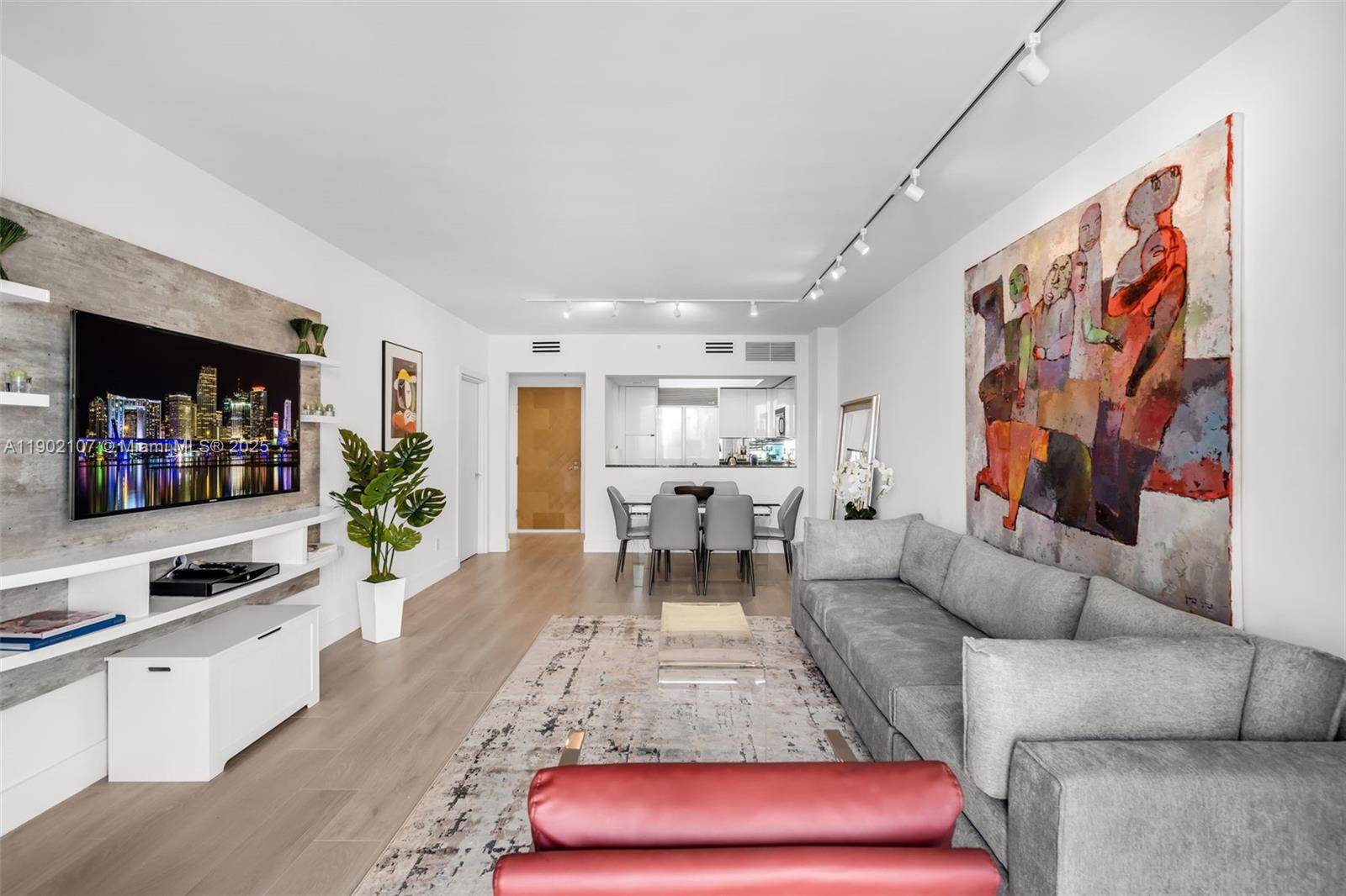 A modern living room features a grey sofa, large abstract wall art, and a television — 1500 Ocean Dr # 1109, Miami Beach FL 33139, MIAMI BEACH, FL