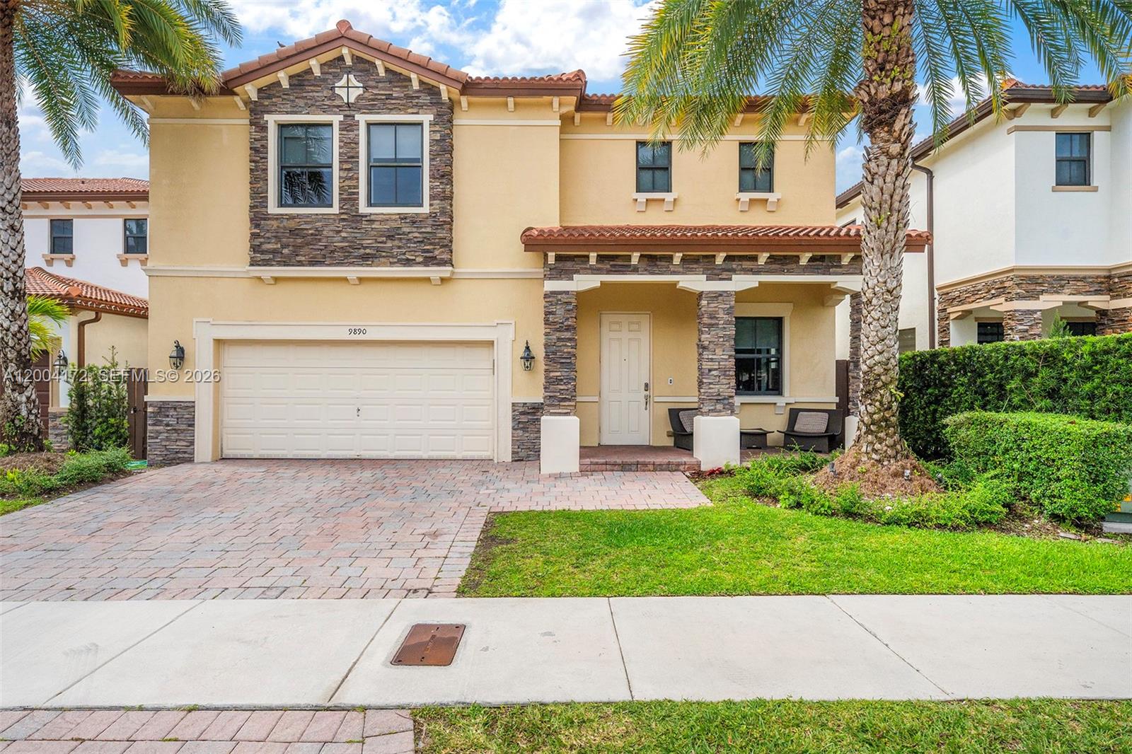 A two-story stucco house with a stone facade, tile roof, and a paved driveway — 9890 NW 86th Ter, Doral FL 33178, DORAL, FL