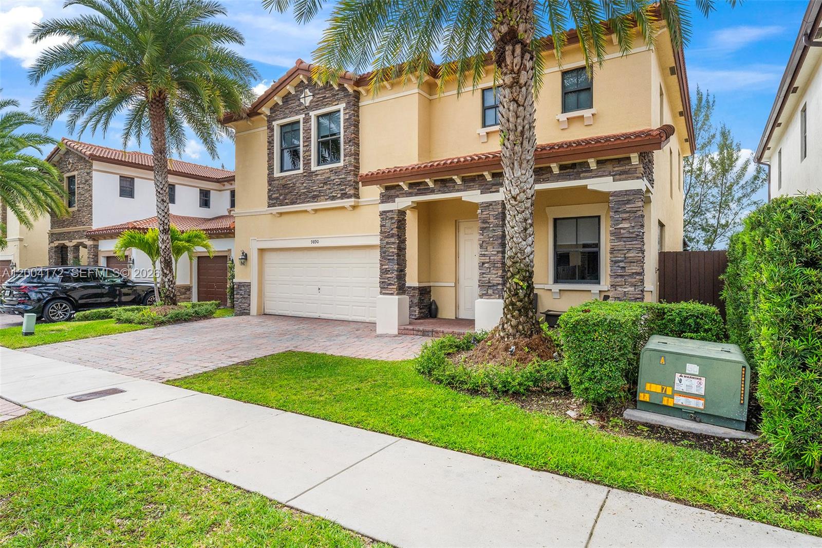 A two-story house with a stone facade, a two-car garage, and a palm tree — 9890 NW 86th Ter, Doral FL 33178, DORAL, FL