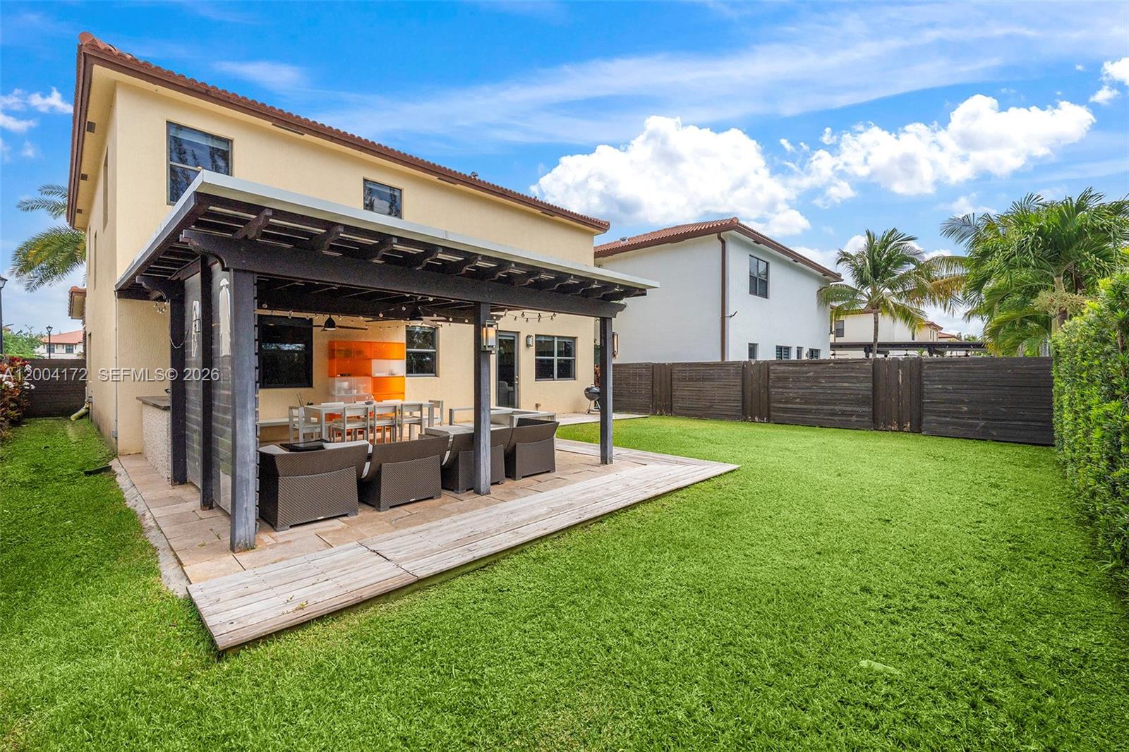 A backyard features a covered patio with outdoor furniture, a wooden deck, and a lawn — 9890 NW 86th Ter, Doral FL 33178, DORAL, FL