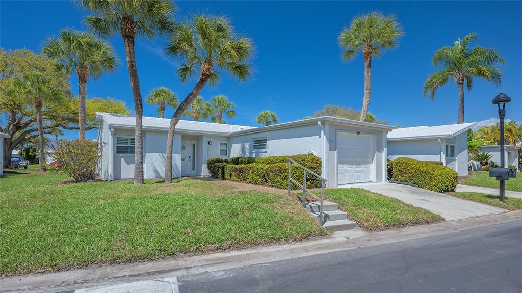 A white single-story house with a garage, palm trees, and a small set of front steps — 119 WHISPERING SANDS CIRCLE UNIT V36, SARASOTA, FL