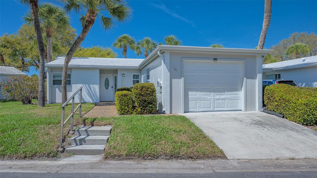A single-story white house with a garage, a front lawn, and palm trees — 119 WHISPERING SANDS CIRCLE UNIT V36, SARASOTA, FL