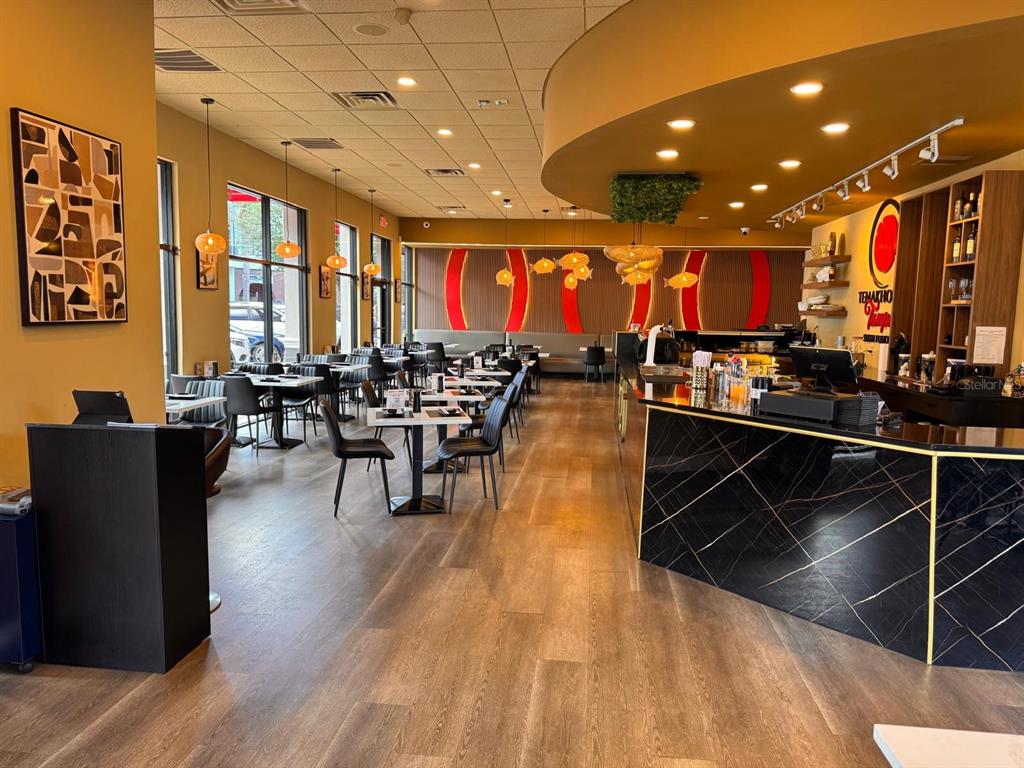 The interior of a modern restaurant features a black marble bar, dining tables, and pendant lighting — 9664 W LINEBAUGH AVE, TAMPA, FL