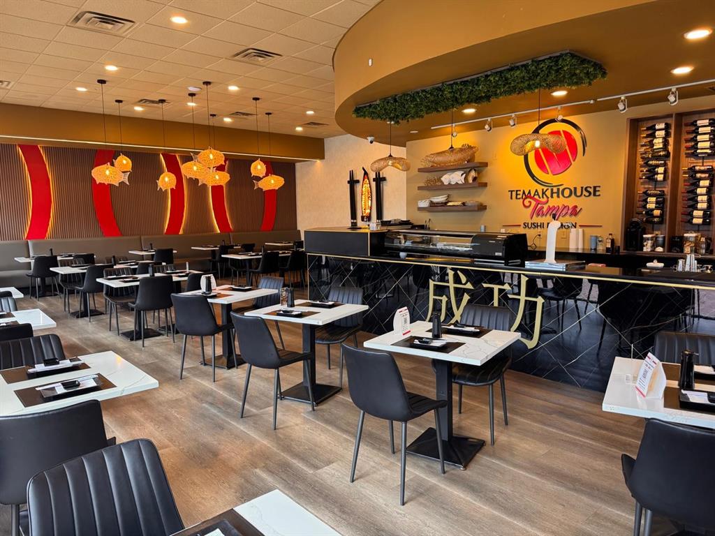 A modern restaurant interior features a sushi bar, tables with black chairs, and pendant lighting — 9664 W LINEBAUGH AVE, TAMPA, FL