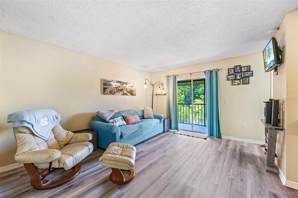 A living room features a blue sofa, a tan leather recliner, and a sliding glass door — 275 SPRING DRIVE UNIT 4, MERRITT ISLAND, FL