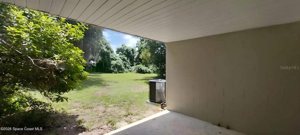 A concrete patio overlooks a grassy backyard with a central air conditioning unit — 3509 BREVARD ROAD, MIMS, FL