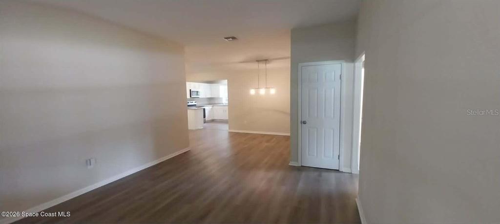 A living area with wood-look flooring leads to a kitchen with white cabinets — 3509 BREVARD ROAD, MIMS, FL