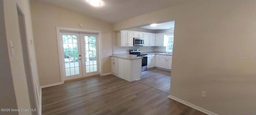 A kitchen with white cabinets and a dining area featuring glass doors to the outside — 3509 BREVARD ROAD, MIMS, FL