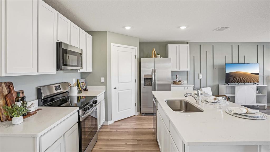 A modern kitchen features white cabinets, stainless steel appliances, and a large central island — 2152 NE 28TH PLACE, OCALA, FL