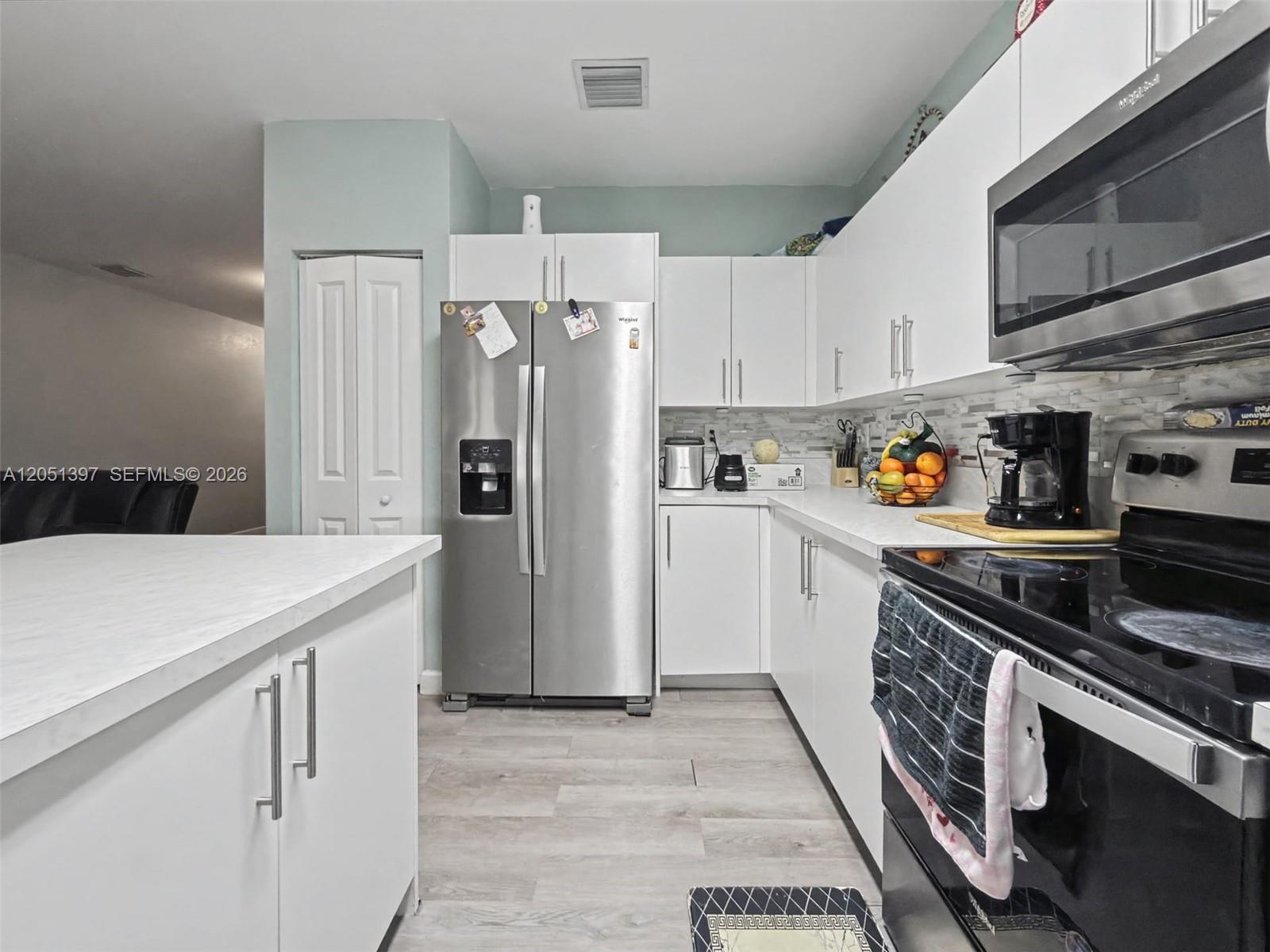 A kitchen features white cabinets, stainless steel appliances, and a light-colored countertop — 396 NW 12th Pl, Florida City FL 33034, FLORIDA CITY, FL